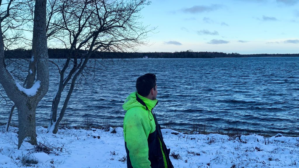 Flexens' Head of Commercial and Energy Modelling Specialist Edvard Nordlund standing on a snowy shoreline in the Åland Islands, looking out over the sea.